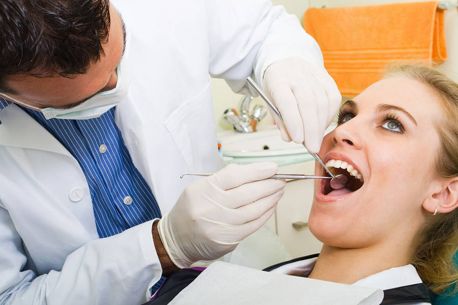 dentist examining patient with dental instruments